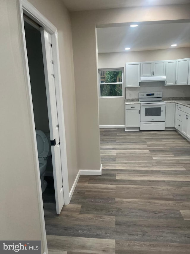 kitchen with hardwood / wood-style flooring, white range with electric cooktop, and white cabinets