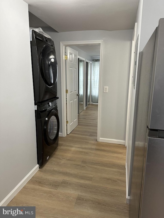 washroom with light wood-type flooring and stacked washing maching and dryer