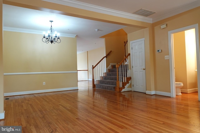 interior space featuring wood-type flooring, ornamental molding, and an inviting chandelier