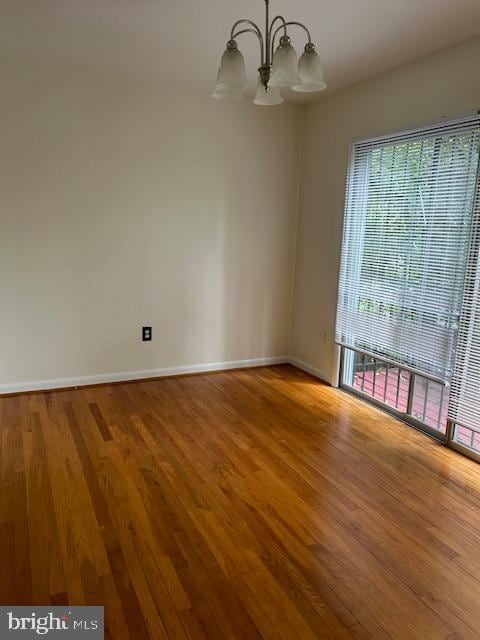 unfurnished room featuring plenty of natural light, a notable chandelier, and wood-type flooring