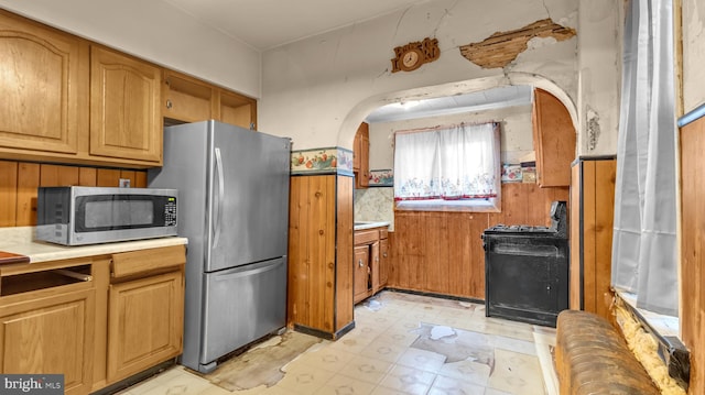 kitchen featuring appliances with stainless steel finishes and wood walls