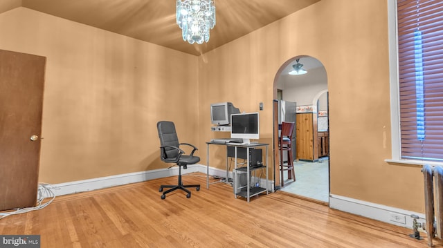 home office featuring radiator heating unit, wood-type flooring, vaulted ceiling, and an inviting chandelier