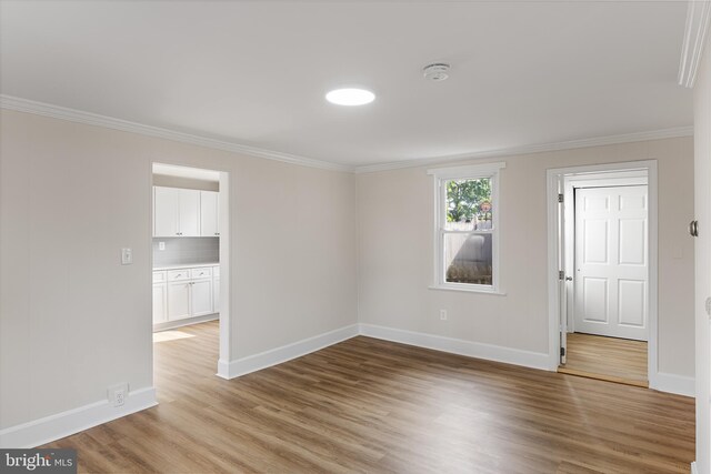 spare room featuring light hardwood / wood-style floors and crown molding