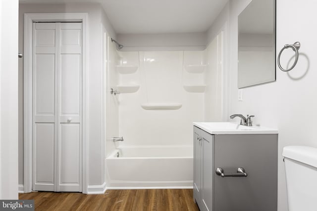 full bathroom with hardwood / wood-style floors, bathing tub / shower combination, vanity, and toilet