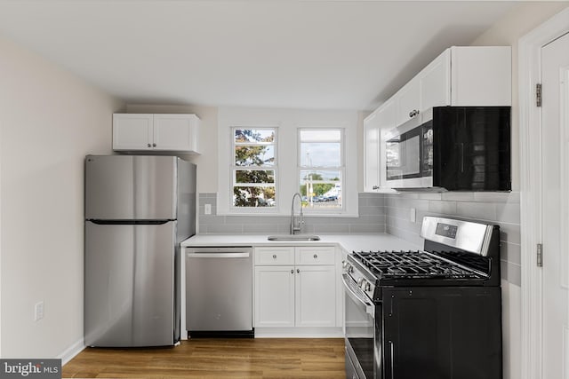 kitchen featuring stainless steel appliances, white cabinets, light hardwood / wood-style floors, and sink