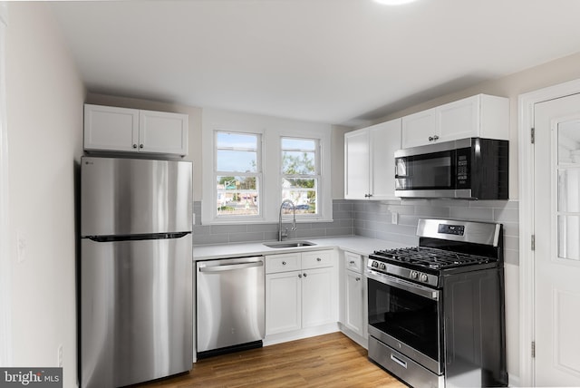 kitchen featuring sink, tasteful backsplash, light hardwood / wood-style flooring, white cabinetry, and stainless steel appliances