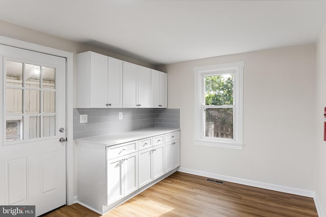 kitchen featuring light hardwood / wood-style floors, tasteful backsplash, and white cabinetry