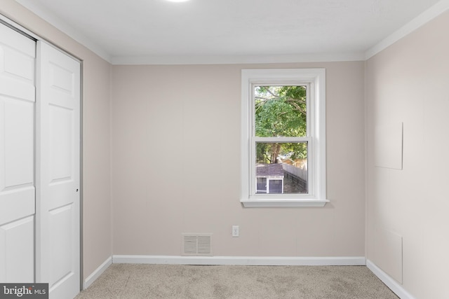 unfurnished bedroom featuring crown molding, light carpet, and a closet