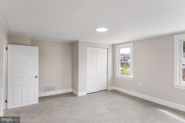 unfurnished bedroom with a closet and light colored carpet