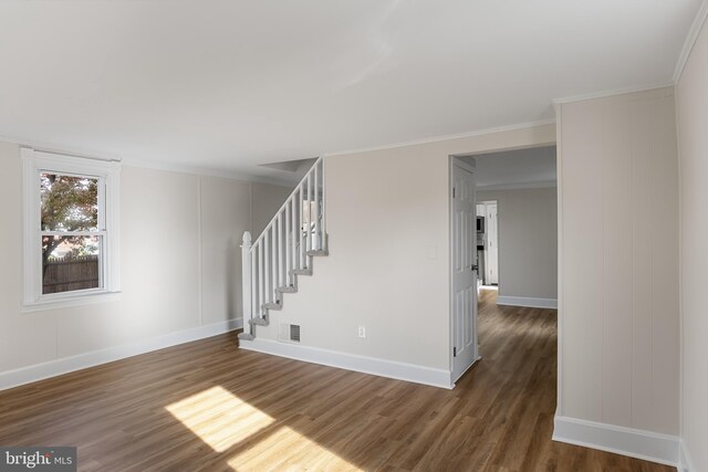 empty room featuring ornamental molding and dark wood-type flooring