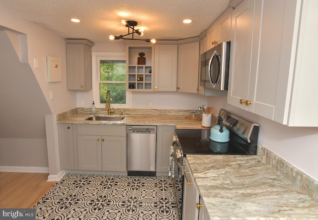 kitchen featuring light stone countertops, appliances with stainless steel finishes, sink, a textured ceiling, and an inviting chandelier