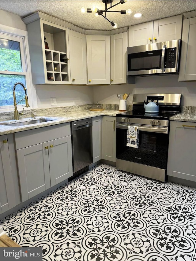 kitchen with gray cabinetry, stainless steel appliances, a textured ceiling, and sink