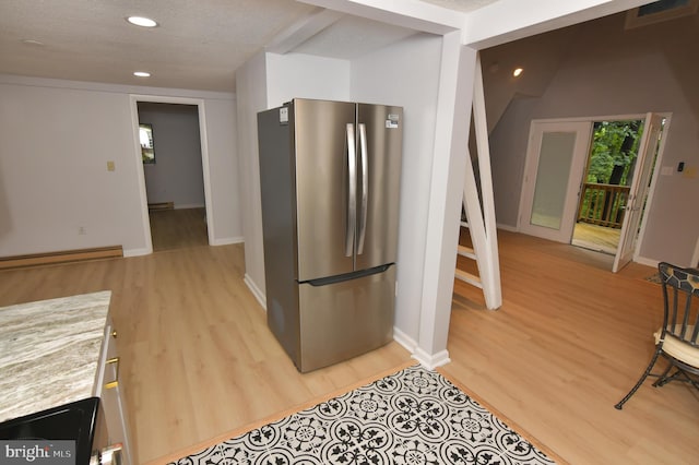 kitchen featuring a textured ceiling, stainless steel refrigerator, light hardwood / wood-style flooring, and baseboard heating