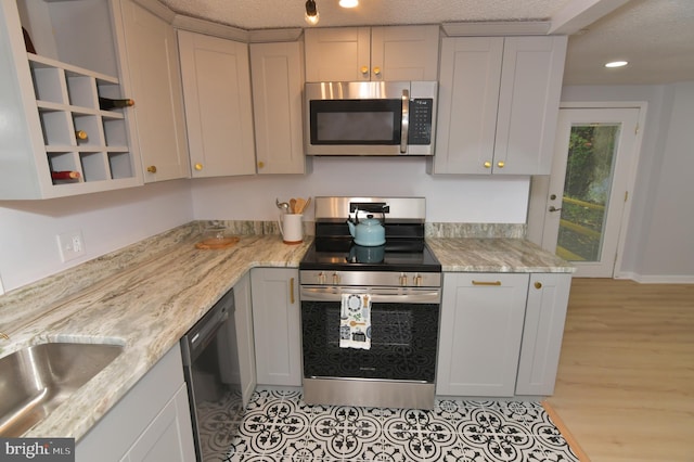 kitchen featuring appliances with stainless steel finishes, a textured ceiling, light stone countertops, and light hardwood / wood-style floors