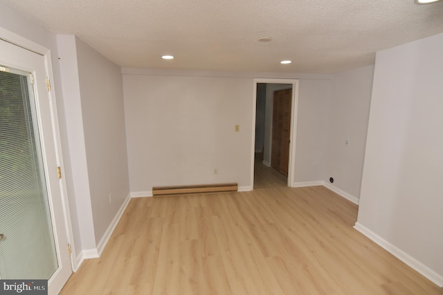 spare room with a baseboard radiator, light hardwood / wood-style flooring, and a textured ceiling