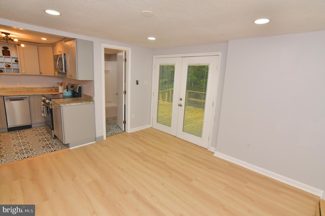 kitchen with a textured ceiling, light hardwood / wood-style flooring, stainless steel appliances, and french doors