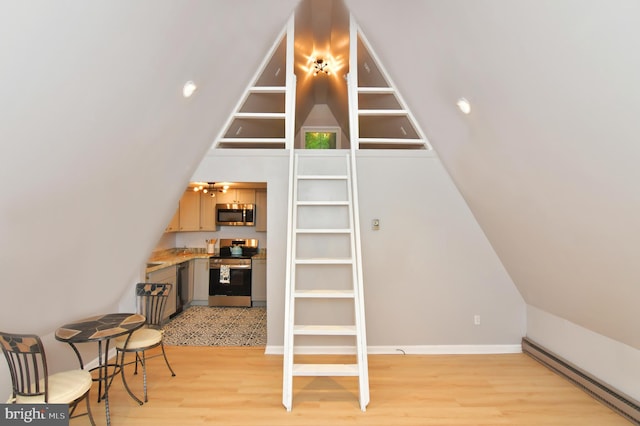 interior space featuring light hardwood / wood-style flooring, a baseboard radiator, and vaulted ceiling