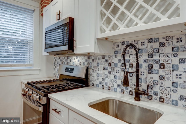 kitchen with appliances with stainless steel finishes, decorative backsplash, white cabinetry, light stone countertops, and sink