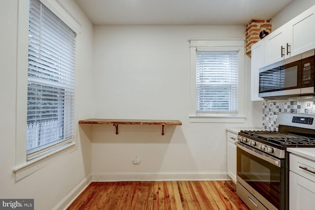 kitchen with light wood-type flooring, tasteful backsplash, stainless steel appliances, and white cabinets