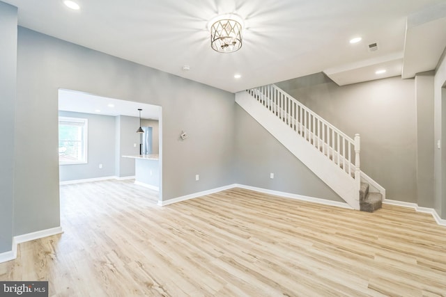 unfurnished living room featuring light hardwood / wood-style flooring and a chandelier