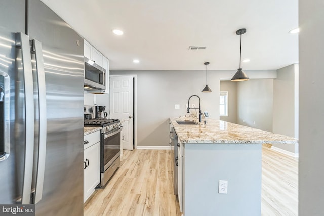 kitchen featuring white cabinets, an island with sink, appliances with stainless steel finishes, and sink