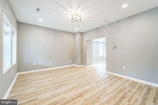 empty room featuring an inviting chandelier and light hardwood / wood-style flooring