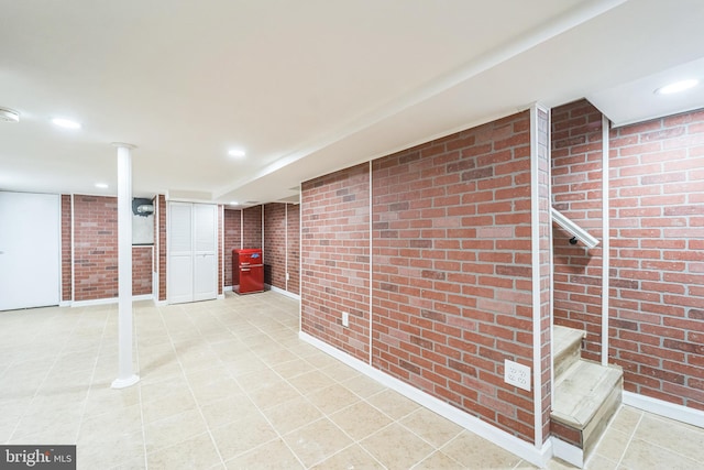 basement featuring tile patterned flooring and brick wall