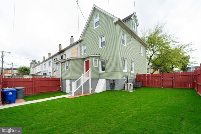 rear view of property featuring a yard and central AC