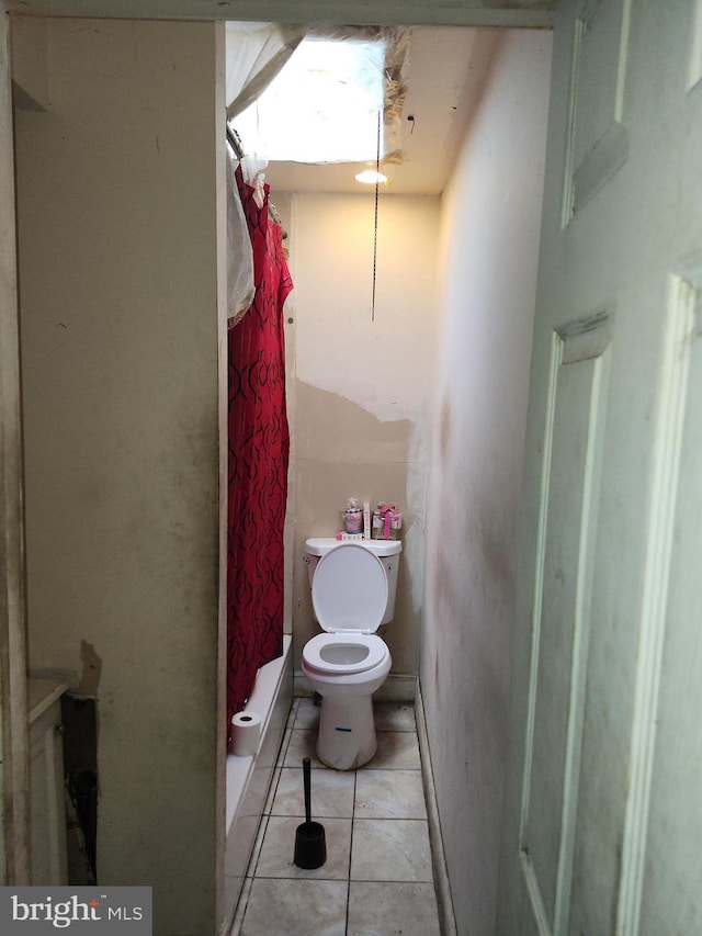 bathroom featuring tile patterned flooring, toilet, and curtained shower