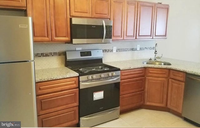 kitchen with light stone counters, sink, stainless steel appliances, and tasteful backsplash