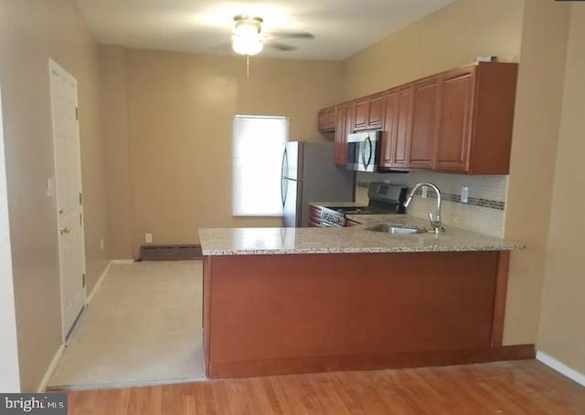 kitchen with light hardwood / wood-style floors, kitchen peninsula, stainless steel appliances, ceiling fan, and sink