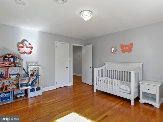 bedroom with a crib and wood-type flooring