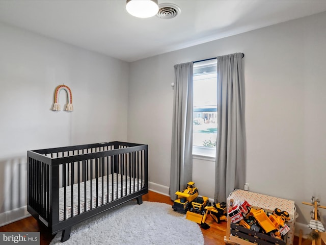 bedroom with a crib and hardwood / wood-style floors