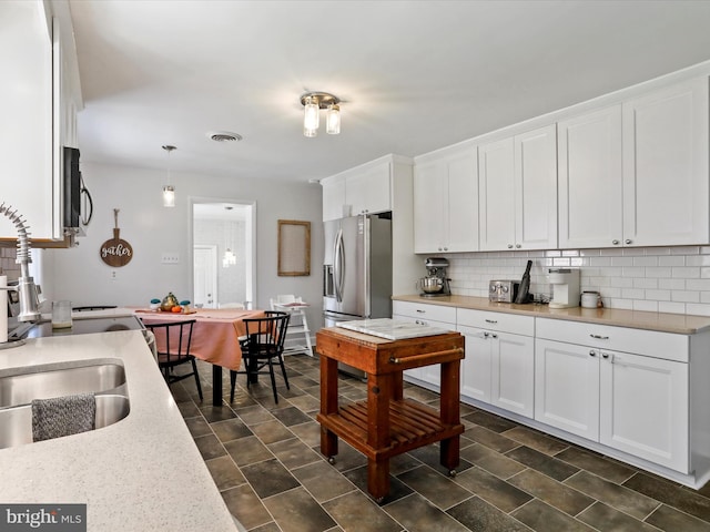 kitchen featuring hanging light fixtures, tasteful backsplash, stainless steel fridge with ice dispenser, and white cabinetry