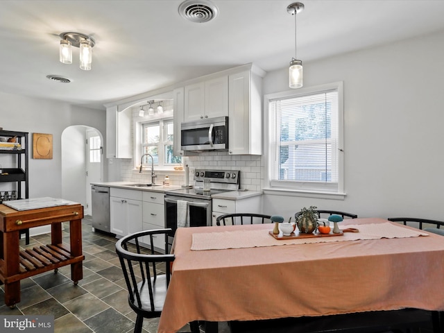 kitchen with appliances with stainless steel finishes, a healthy amount of sunlight, sink, and white cabinets