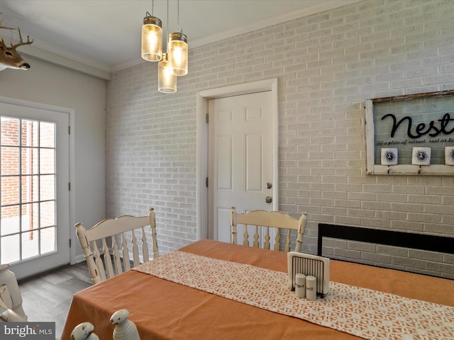 dining space with ornamental molding, light hardwood / wood-style floors, and brick wall