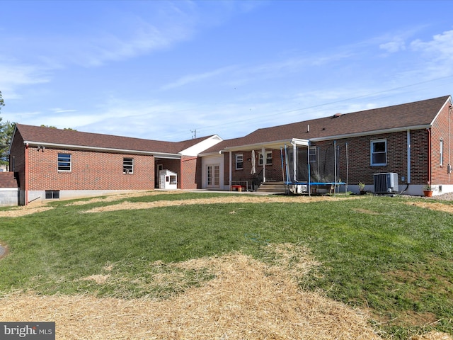 back of property featuring a trampoline, a lawn, and central AC