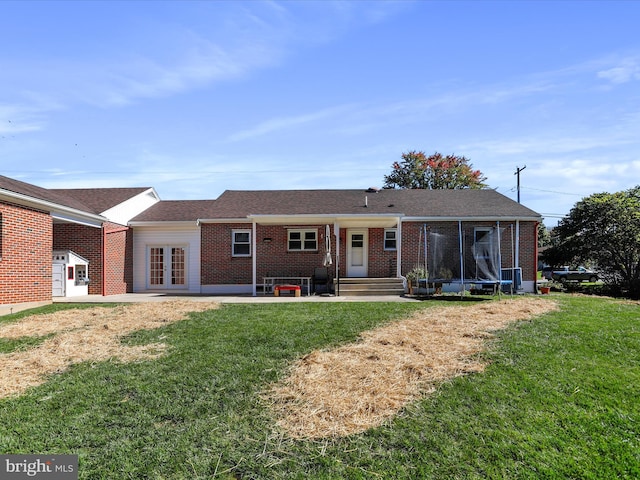 view of front of home with a trampoline, french doors, a front yard, and a patio area