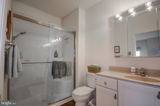 bathroom with wood-type flooring, vanity, a shower with shower door, and toilet