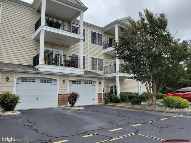 townhome / multi-family property with a garage, driveway, and brick siding