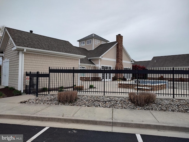 view of front facade featuring a fenced front yard and a shingled roof