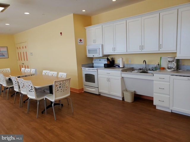 kitchen with dark wood finished floors, white appliances, a sink, and white cabinetry