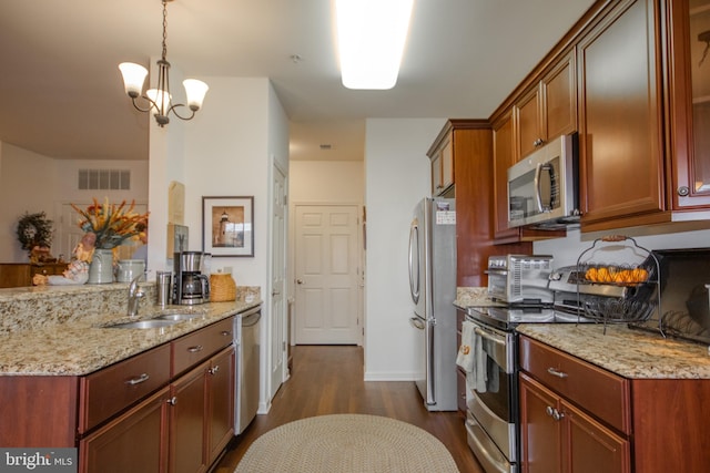 kitchen with decorative light fixtures, stainless steel appliances, dark wood-type flooring, and light stone countertops