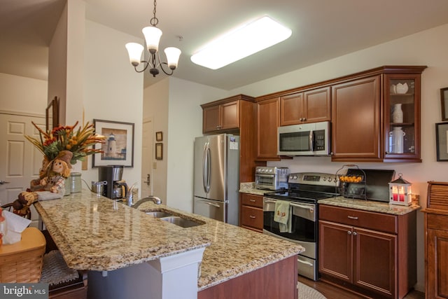 kitchen featuring pendant lighting, kitchen peninsula, appliances with stainless steel finishes, a breakfast bar, and light stone countertops