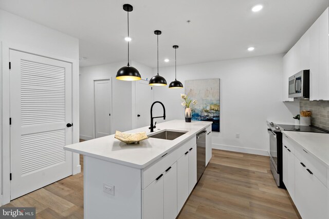 kitchen featuring an island with sink, white cabinets, appliances with stainless steel finishes, and sink