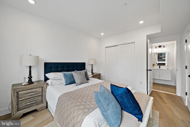 bedroom featuring light hardwood / wood-style floors, ensuite bathroom, and a closet