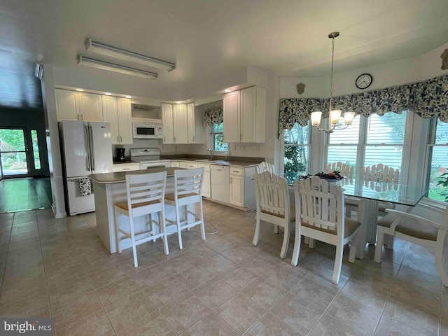 kitchen with white cabinetry, white appliances, a kitchen island, sink, and a chandelier