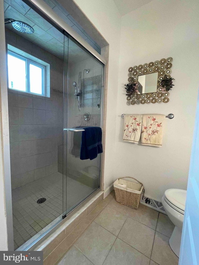 bathroom featuring toilet, a shower with door, and tile patterned floors