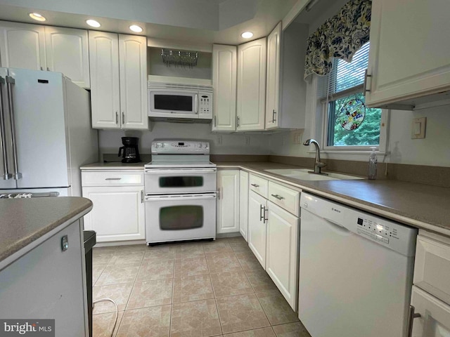 kitchen with white cabinets, white appliances, light tile patterned floors, and sink