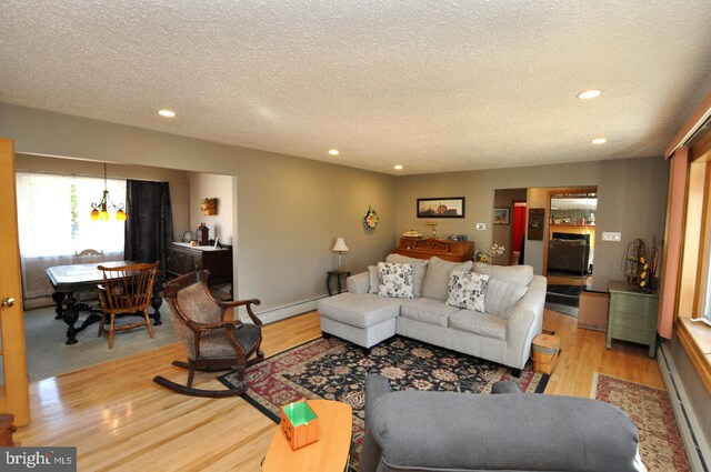 living room with light hardwood / wood-style flooring, a baseboard heating unit, and a textured ceiling